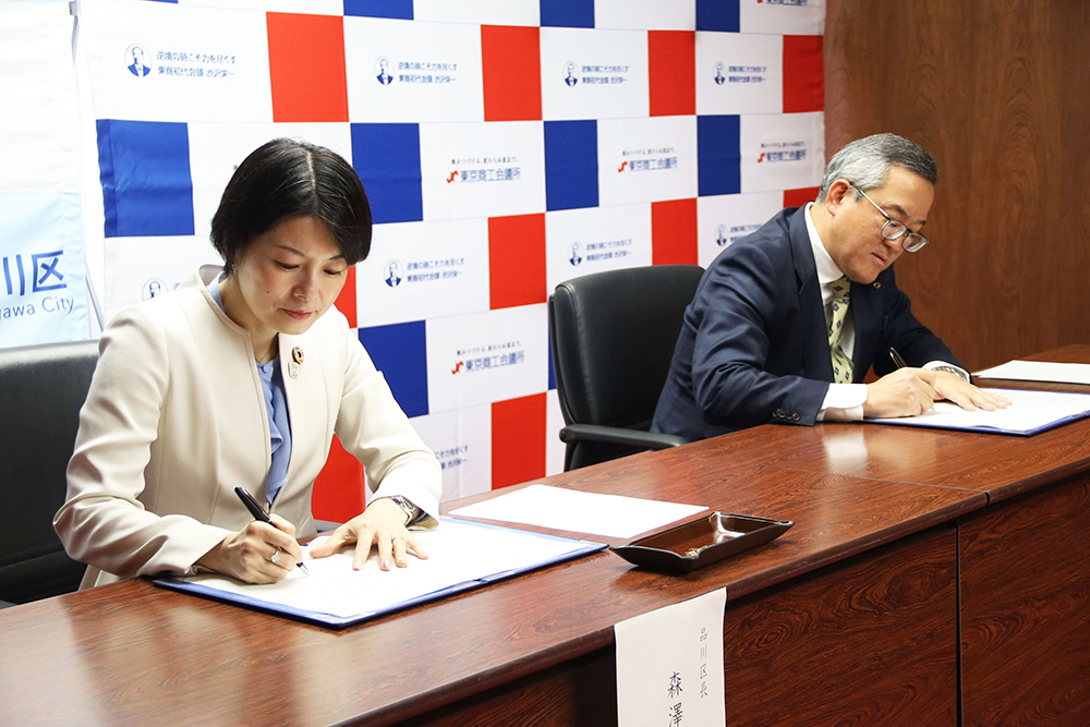 調印する森澤区長と協定書を持ち写真を撮る森澤区長と武田東京商工会議所品川支部会長の画像の画像