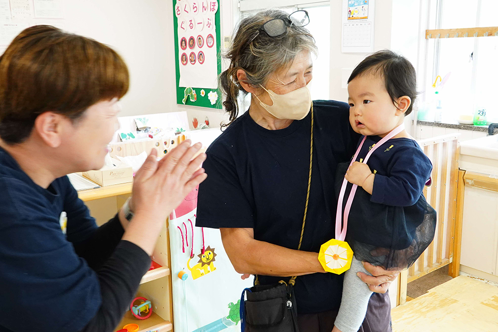 園長先生に抱きかかえられる園児の写真