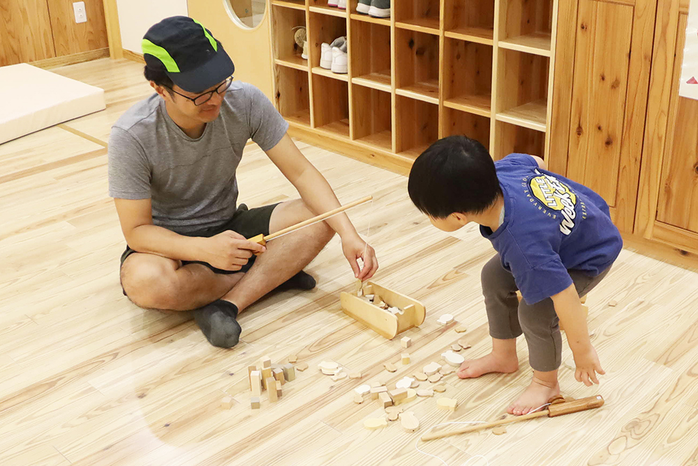 木のおもちゃで遊ぶ親子の画像