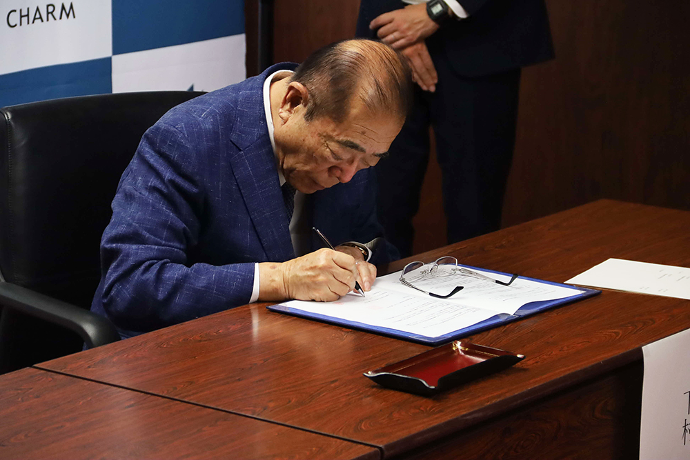 協定書に署名をする下村CEO