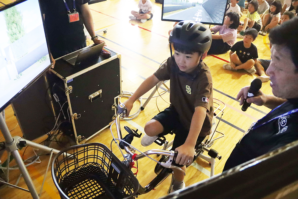自転車シミュレーターを体験する子どもの画像