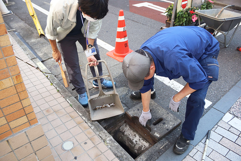 雨水マスを掃除する職員の写真