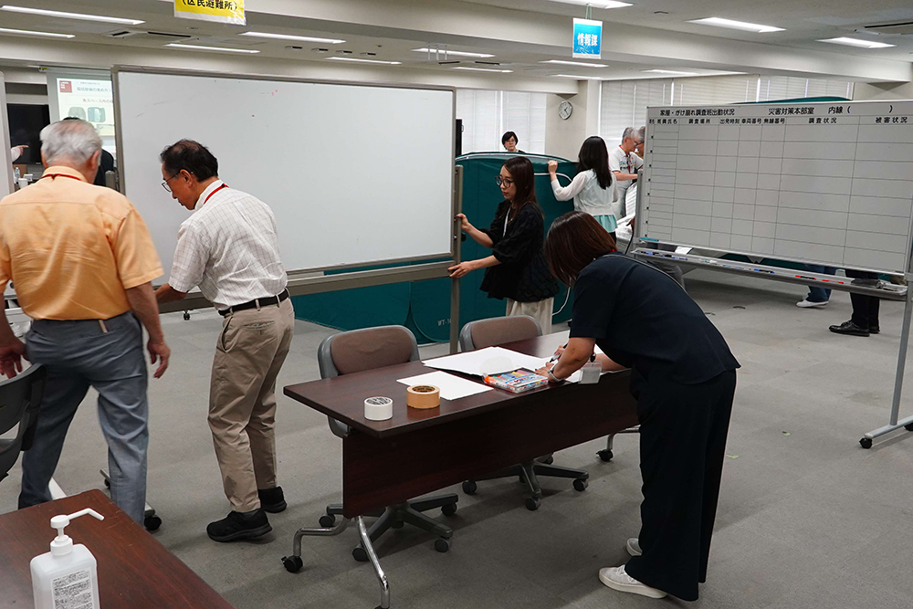 避難所の受付を設置する訓練をする参加者の写真