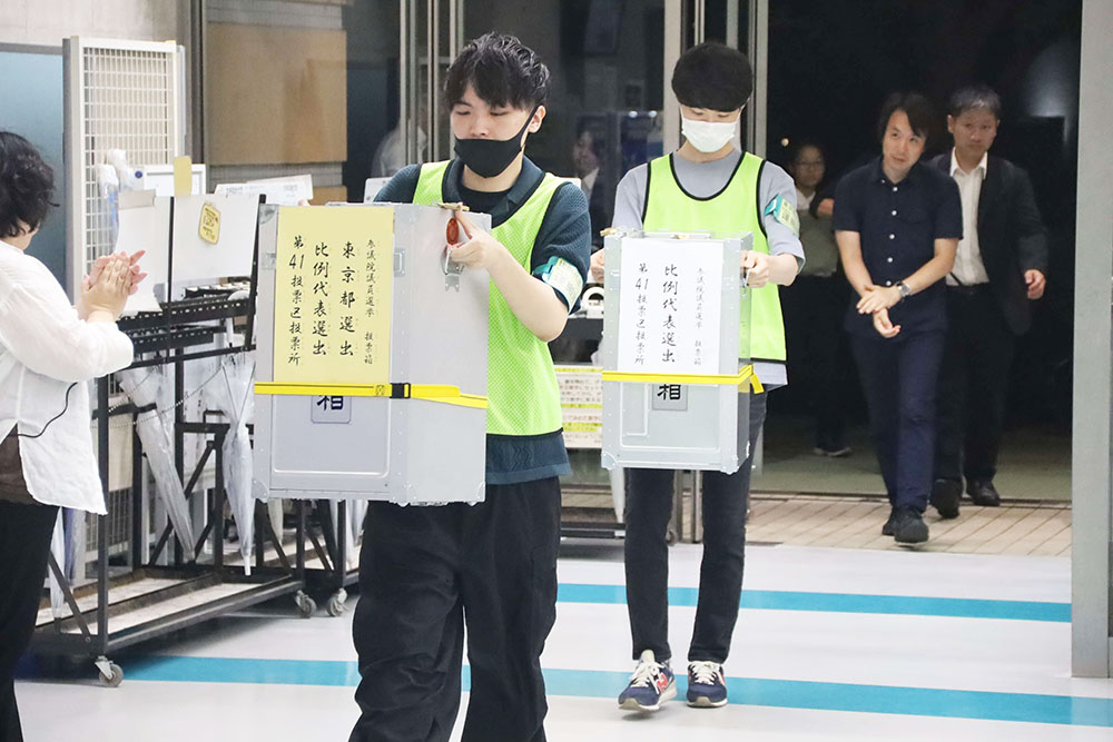 開票所に投票箱を運び込む職員の写真