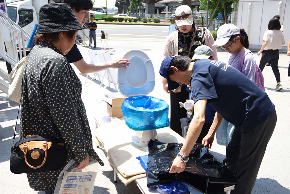 携帯トイレの設置を見学する参加者の画像
