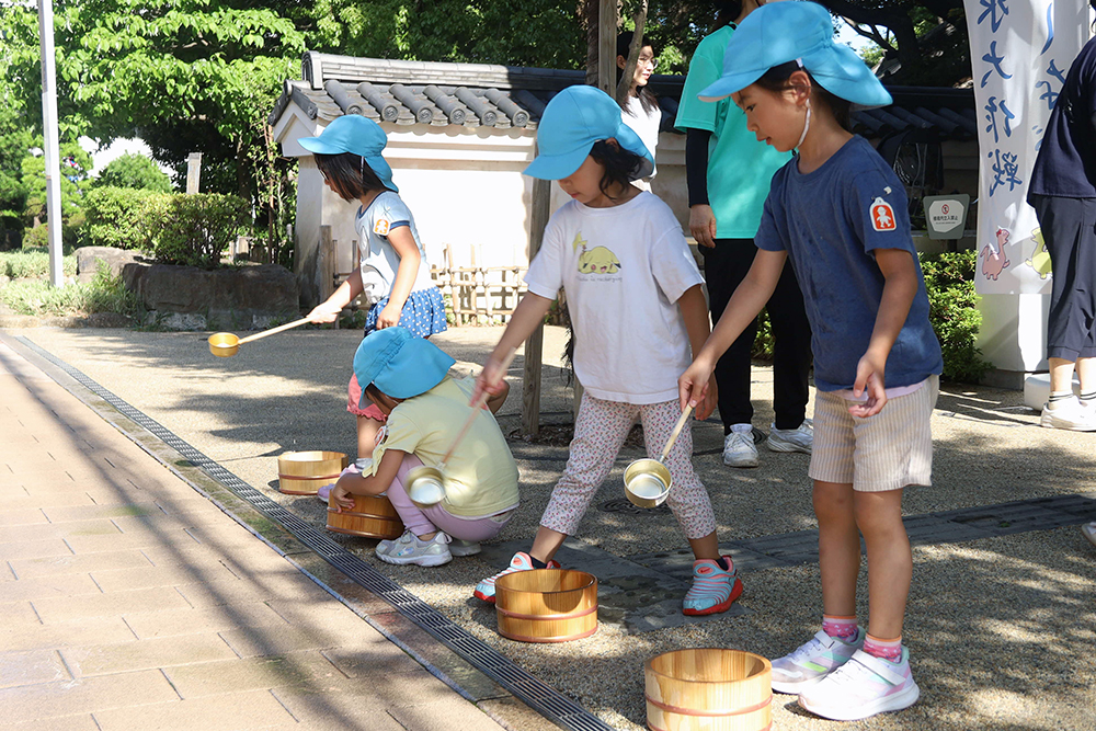 園児たちが打ち水を行っている写真