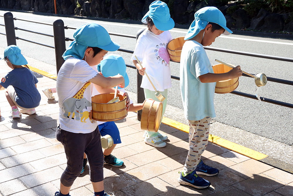 園児たちが打ち水を行っている写真