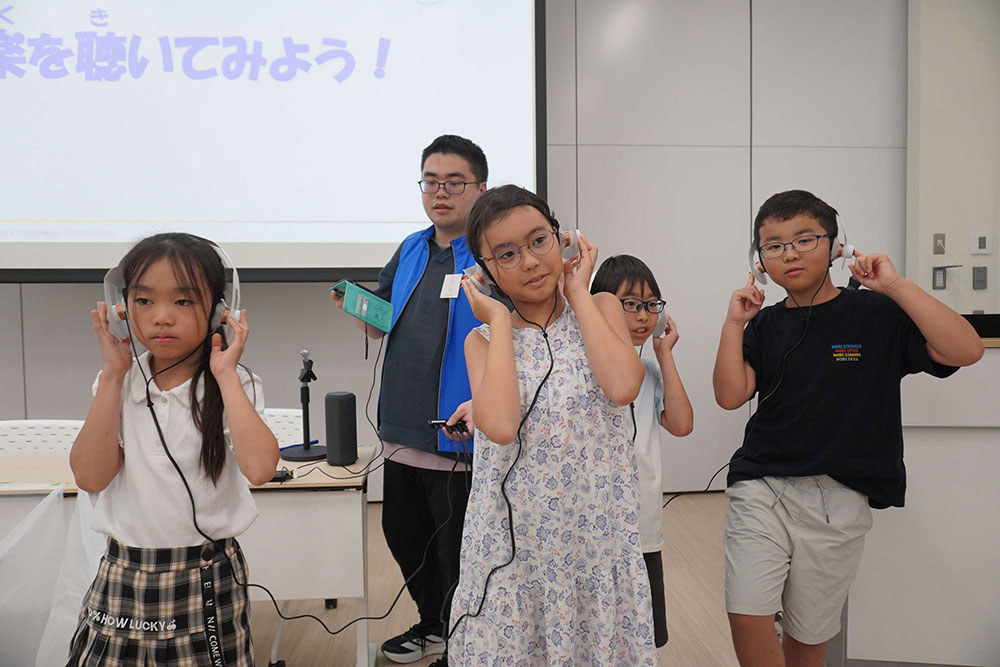 手作りヘッドフォンで音楽を聴く子どもたちの写真