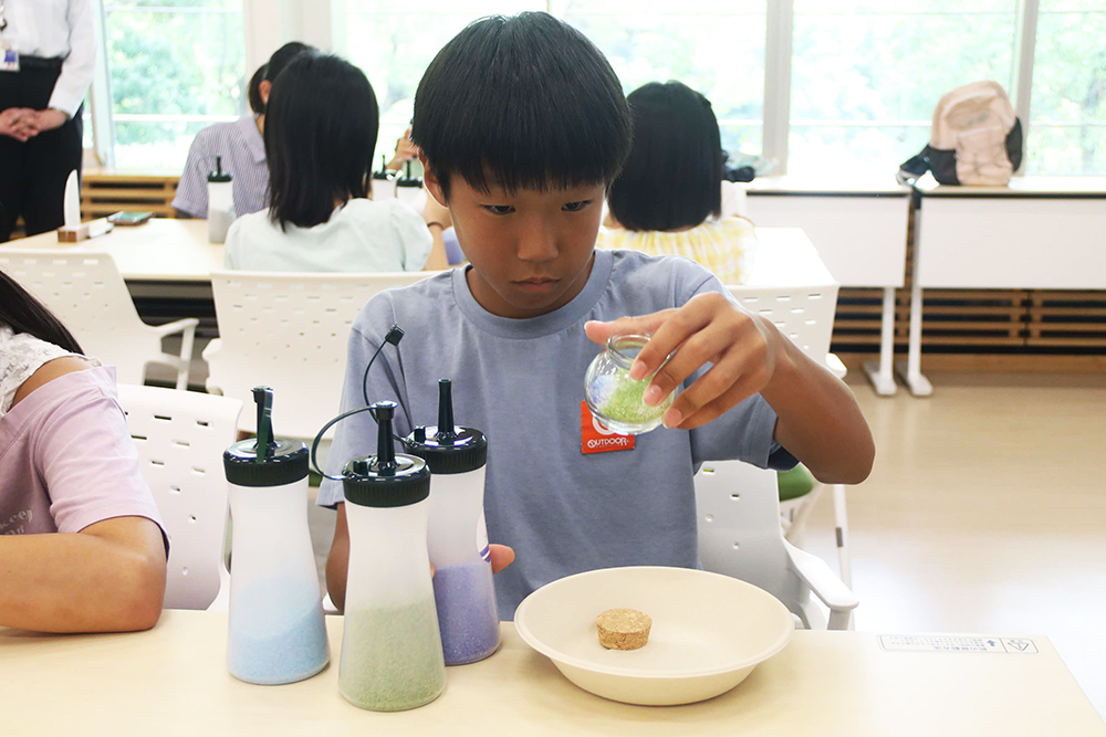 子どもがクリスタルサンドを入れた瓶を眺めている写真