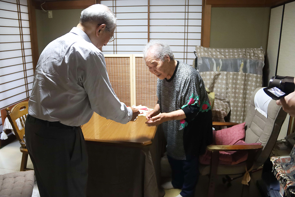 露雪さんにお祝い品を手渡す池田会長の画像