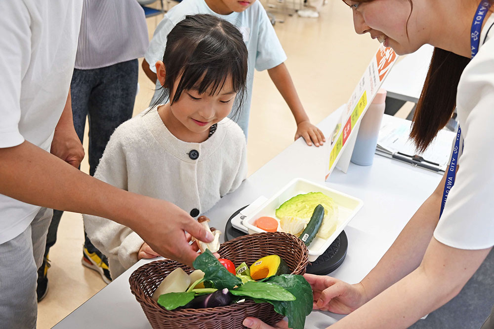 野菜を手に取る児童の写真