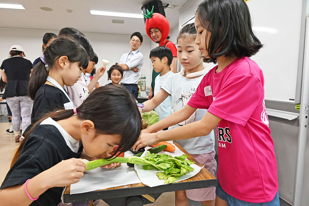 野菜の匂いを嗅ぐ児童の写真