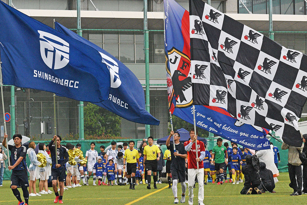 ビッグフラッグとともに入場する選手たちの画像