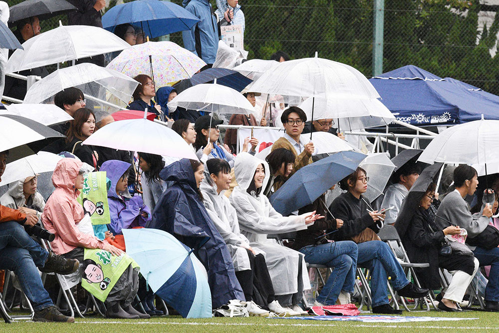 雨の中応援をする観戦者