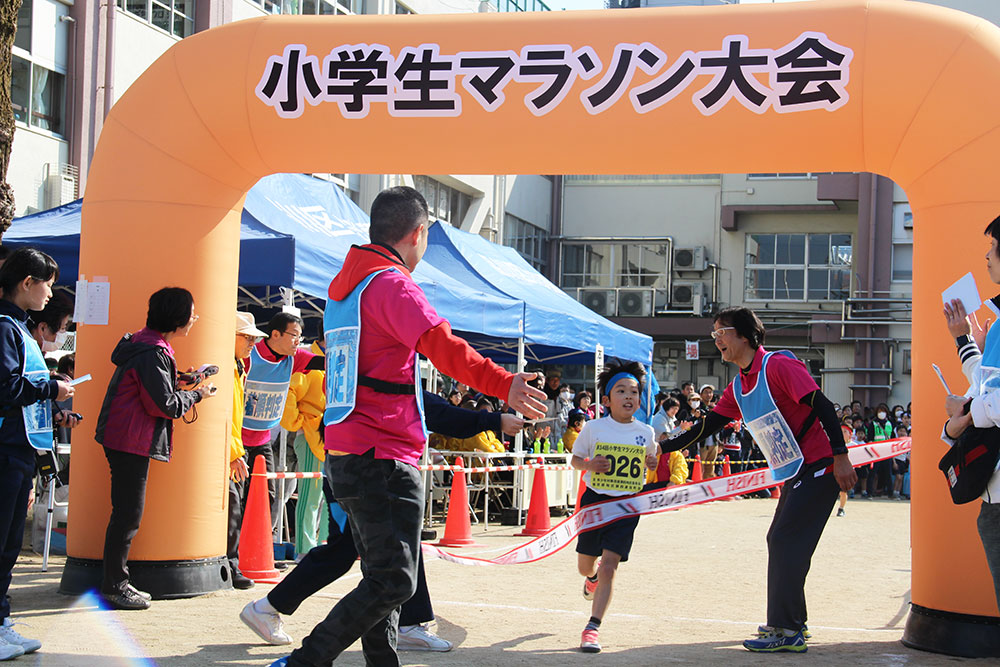 ゴールテープを切る小学生