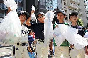 集めたごみを掲げる野球少年