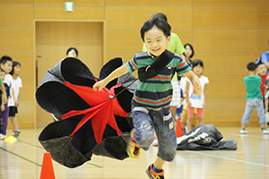 かけっこ教室でパラシュートを背につけ力走する参加者