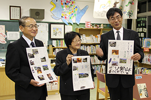 壁新聞を手にする両校長と中野さん