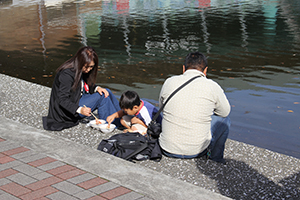 あたたかい日差しの下、水辺でカニ汁に舌鼓を打つ親子