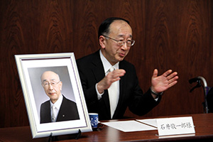 故石井伝一郎氏の遺影を前に謝辞を述べる長男敬一郎氏