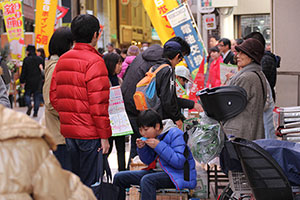 店の横で座り込んで食べる少年