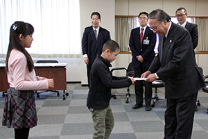 濱野区長に寄付する鈴ケ森小学校児童