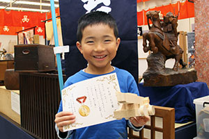 「未来の名工大集合!!」 木材片を使って完成品を披露する子ども