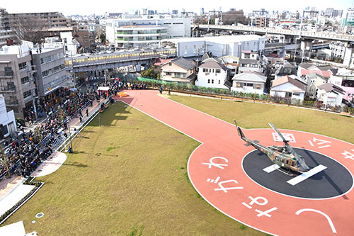 公園に着陸したヘリを見る関係者と近所の人たち