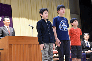 壇上に立つ浅間台小学校囲碁チームの3人