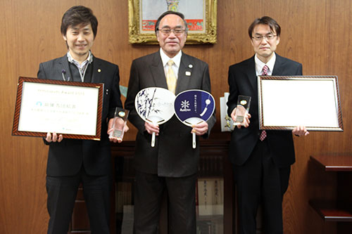 区長と記念撮影する山崎さんと林さん