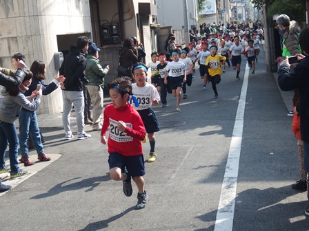 応援する保護者の間を走る選手