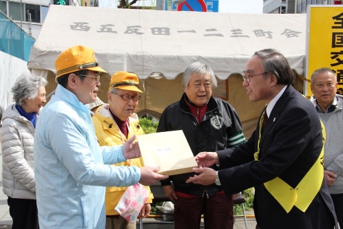 西五反田一・二・三町会の山崎会長に啓発グッズを手渡す濱野区長