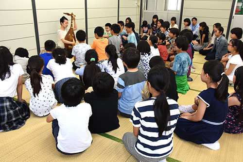 児童に囲まれ琵琶を演奏する榎本さん