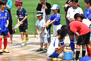 打ち水をする子どもと水を補給する子ども