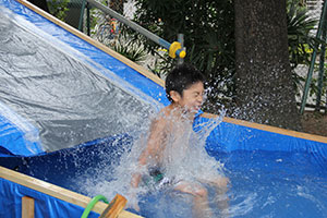 ウォータースライダーを滑り水しぶきを上げる男の子