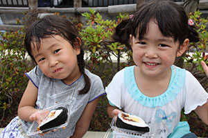 自分たちで作ったのり巻きを笑顔で食べる女の子