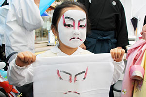 歌舞伎化粧の隈どりを写した晒を見せる女の子