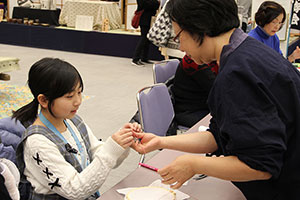 刺繍職人の指導を受ける女の子