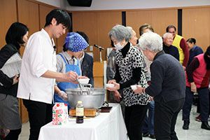 参加者にお吸い物を配る笠原シェフ